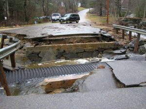 Photo of a culvert that has failed, causing the road to flood and wash out road materials.